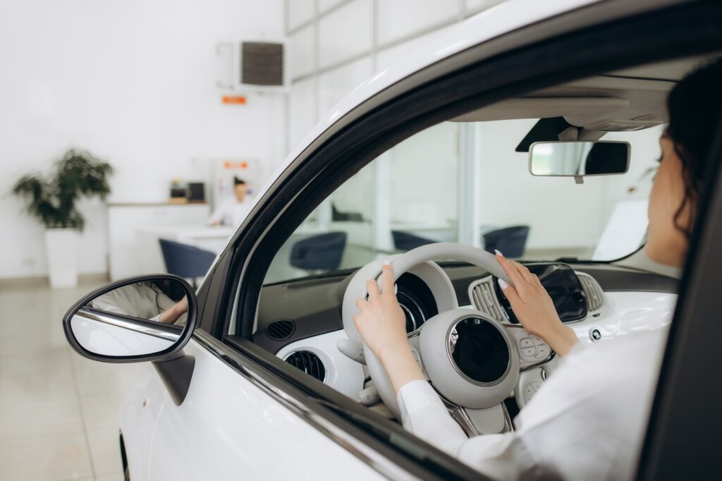 Photo of happy young mixed race woman showing key to her new car. Concept for car rental